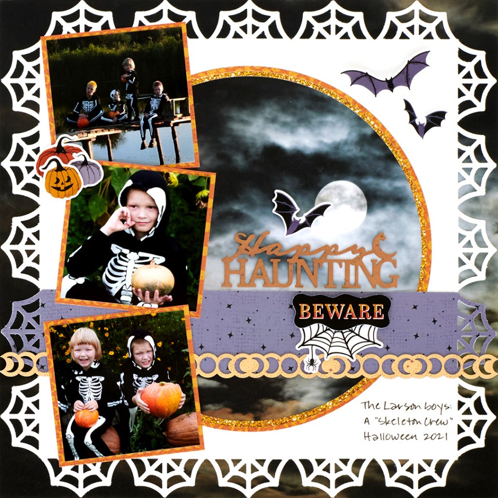 Halloween layout with a spider web frame, three photos of children in Halloween costumes and embellishments.