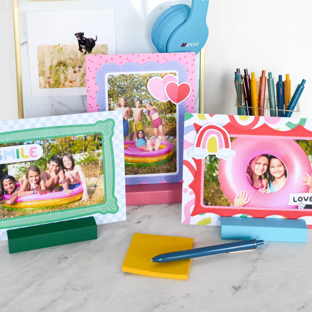 A collection of colorful photo frames displaying images of children enjoying summer activities, with vibrant decorations. In the background, there are stationery items, including a yellow sticky note and a blue pen, along with a pair of blue headphones.