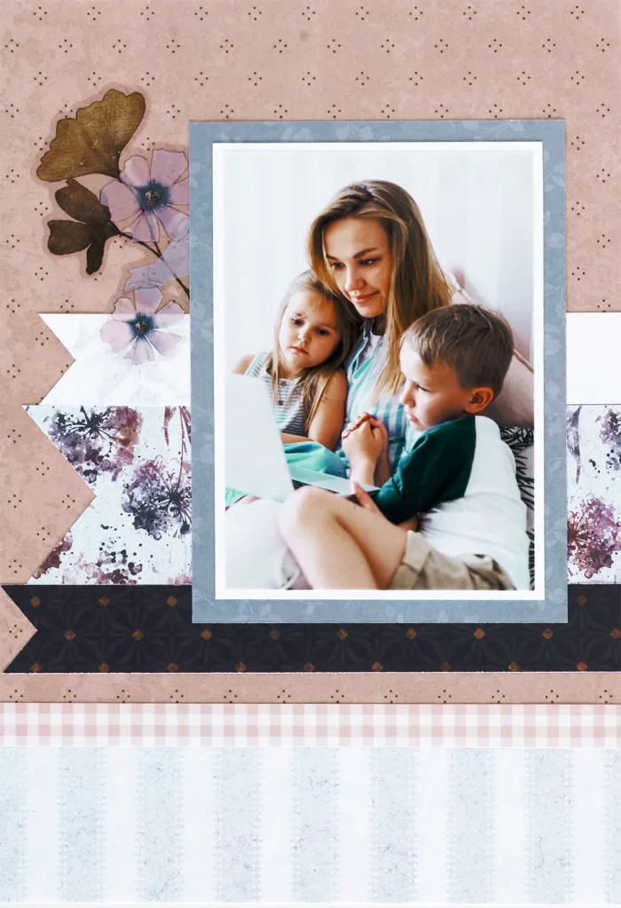 A woman sitting with two children, engrossed in a laptop, surrounded by decorative patterned scrapbook elements.